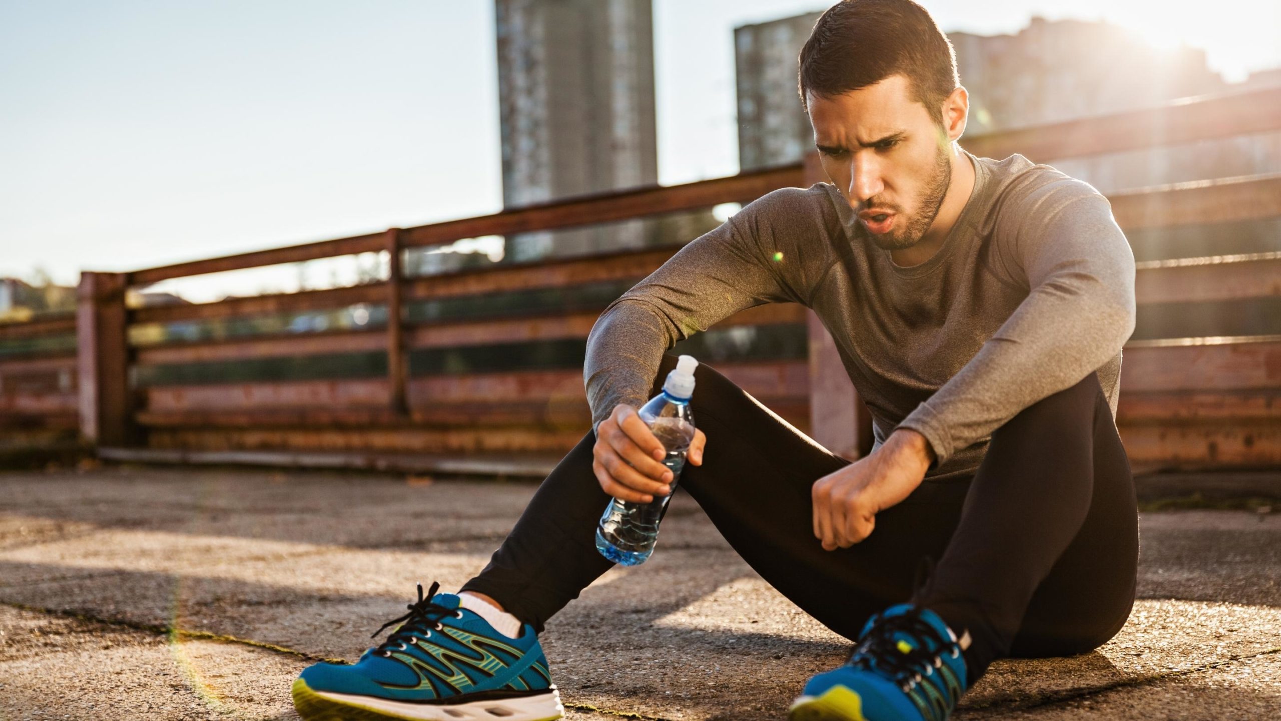 man taking a rest from his workout with electrolyte drink in his hand