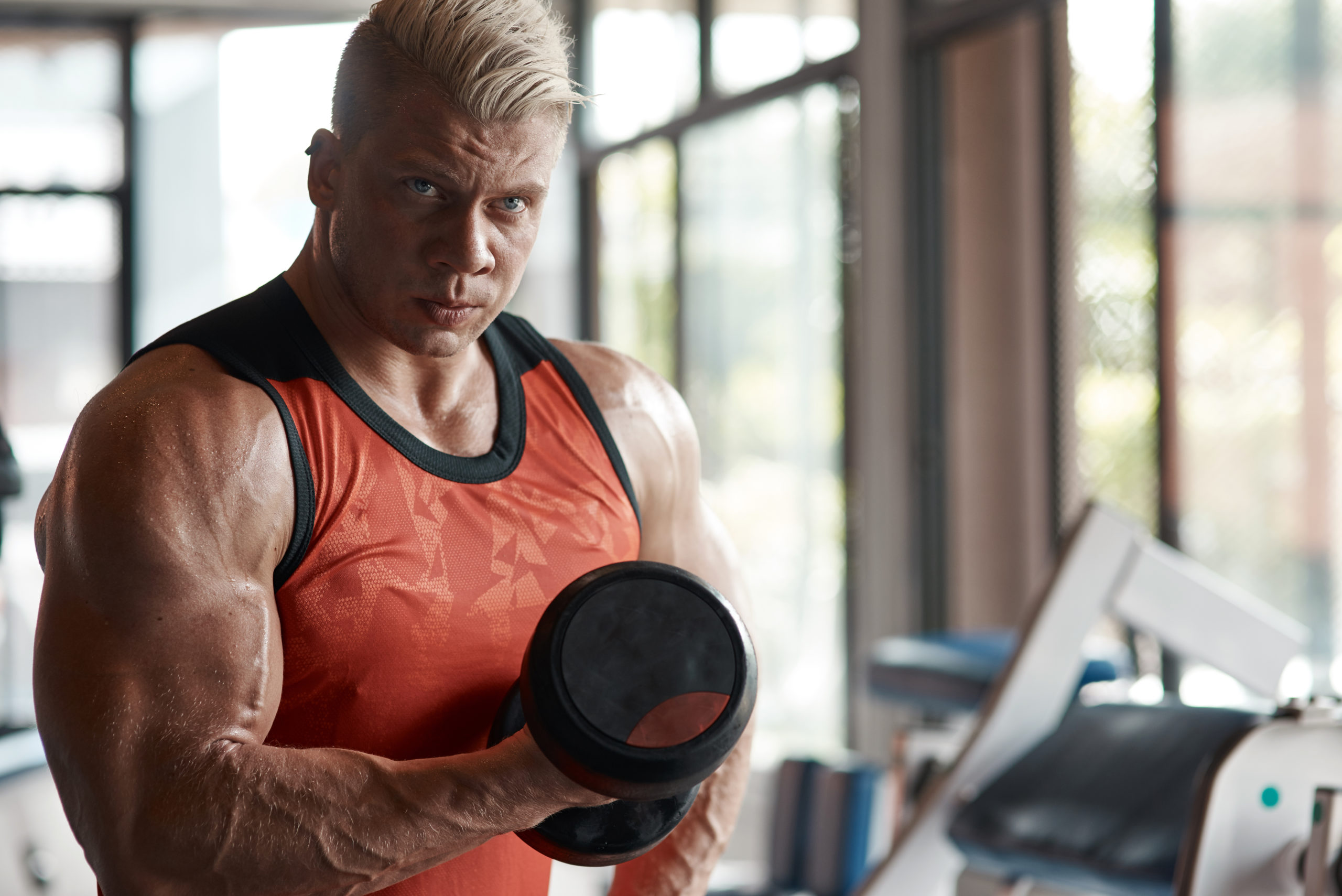 Man with well defined muscular body lifting weights in the gym