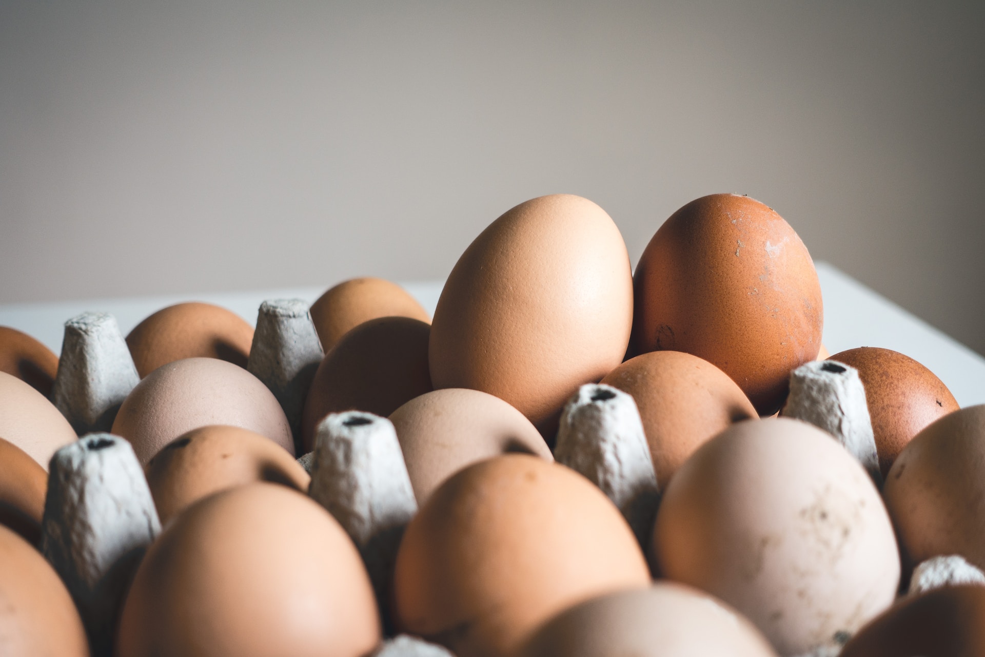 Brown eggs on a gray egg carton placed on a white table