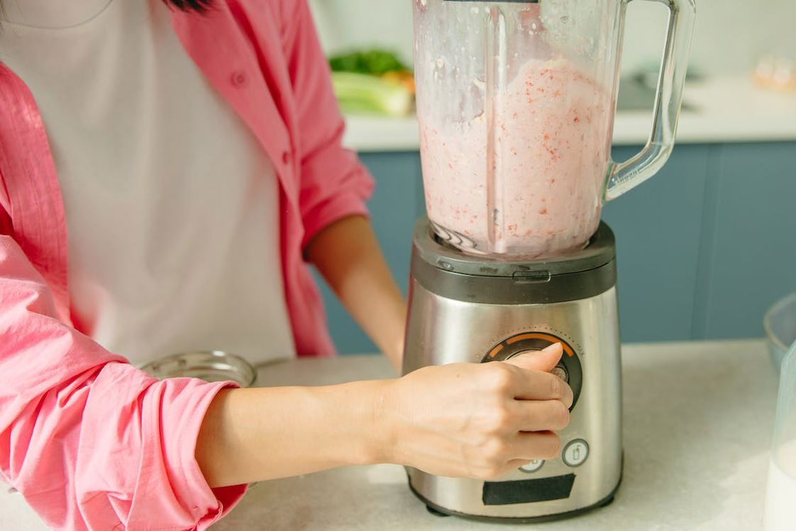 Woman turning the knob of her blender while making a berry smoothie