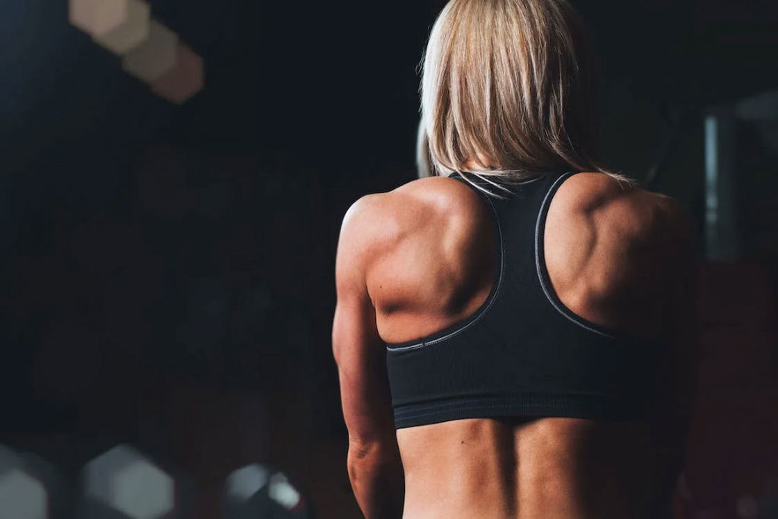 Woman wearing a black sports bra showing off her back muscles