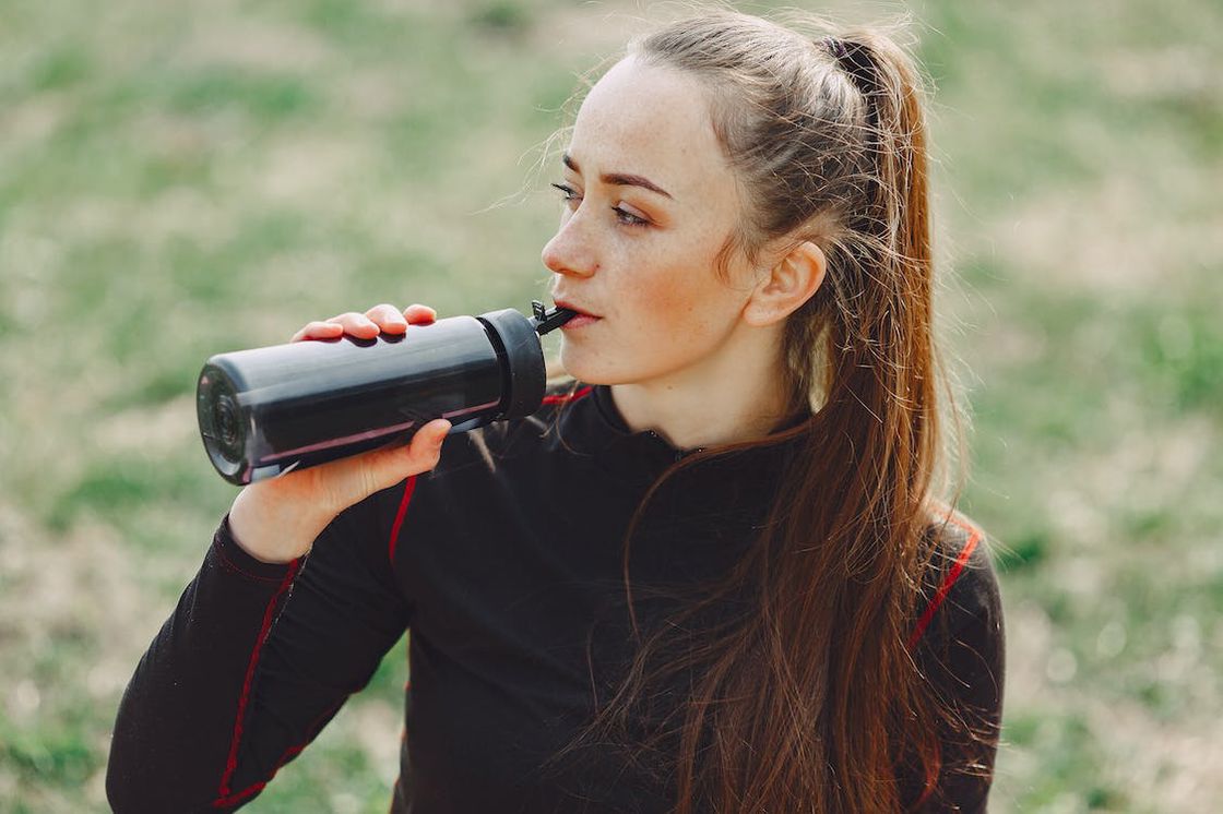 Woman drinking from her black plastic tumbler after working outdoors