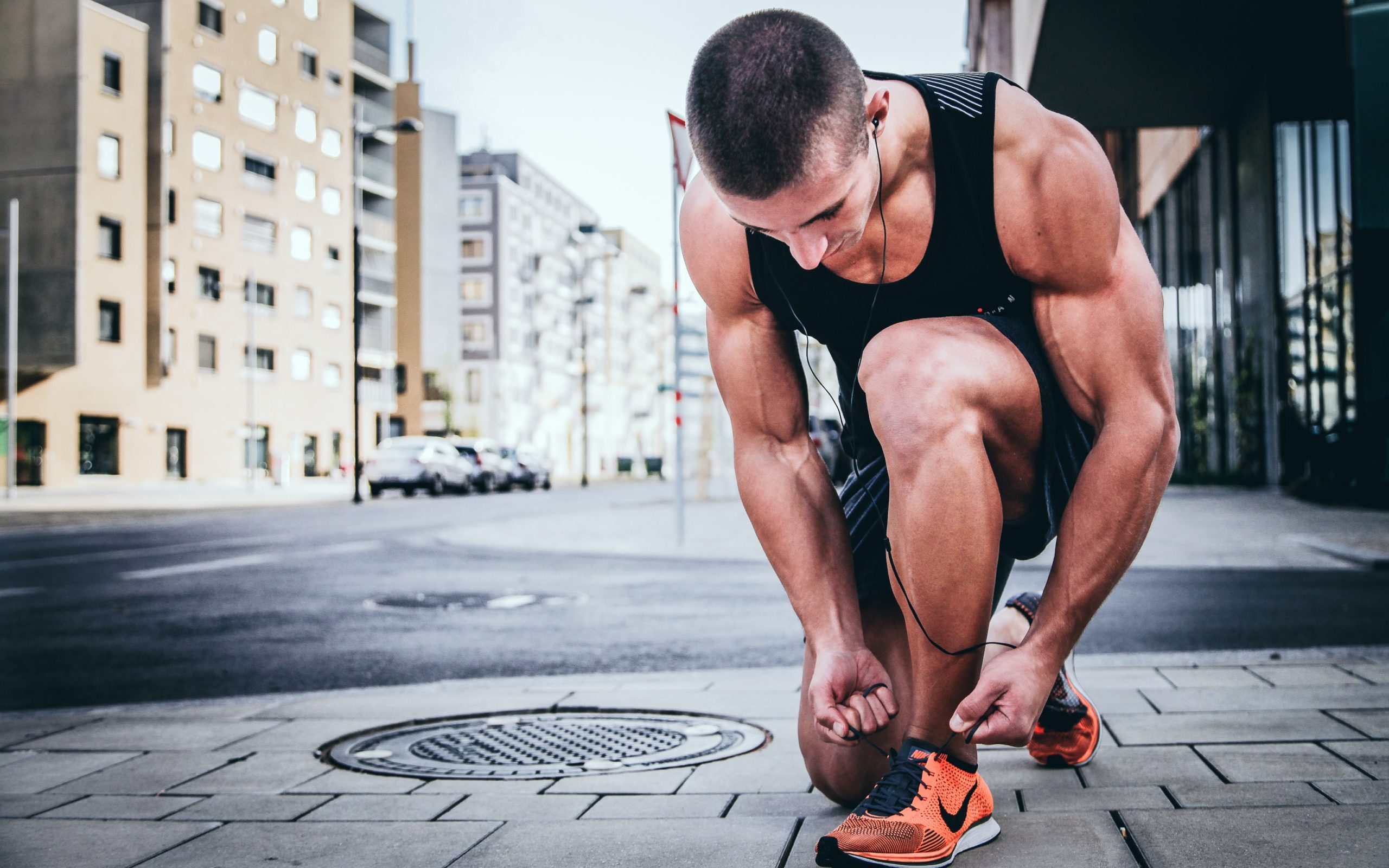 A man with muscles tying his shoe laces