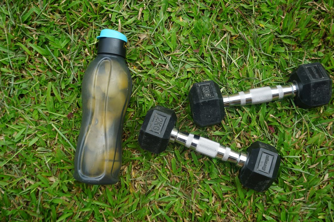 Water bottle and a pair of dumbbells on the grass