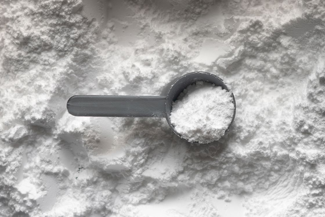 Gray scooper filled with white powder on top of white powder