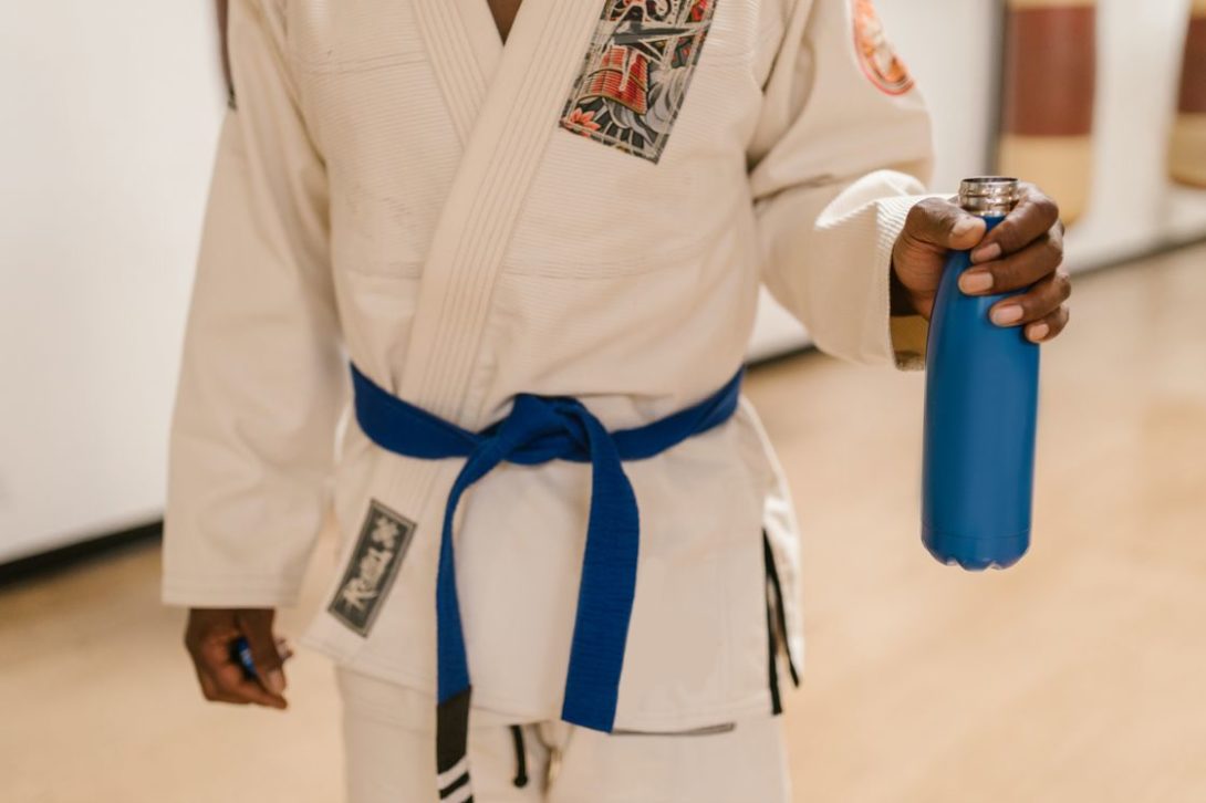 Man wearing a Gi robe while holding a blue water bottle