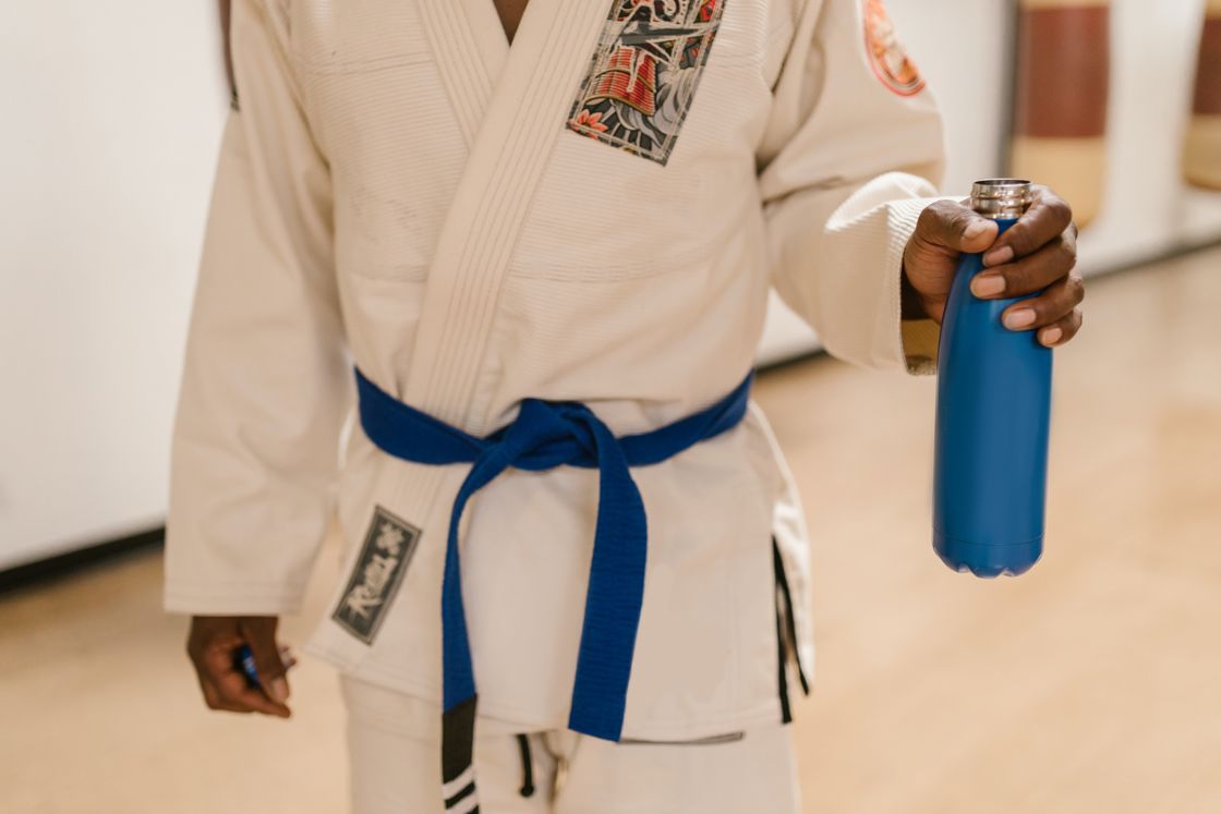 Man wearing a Gi robe while holding a blue water bottle