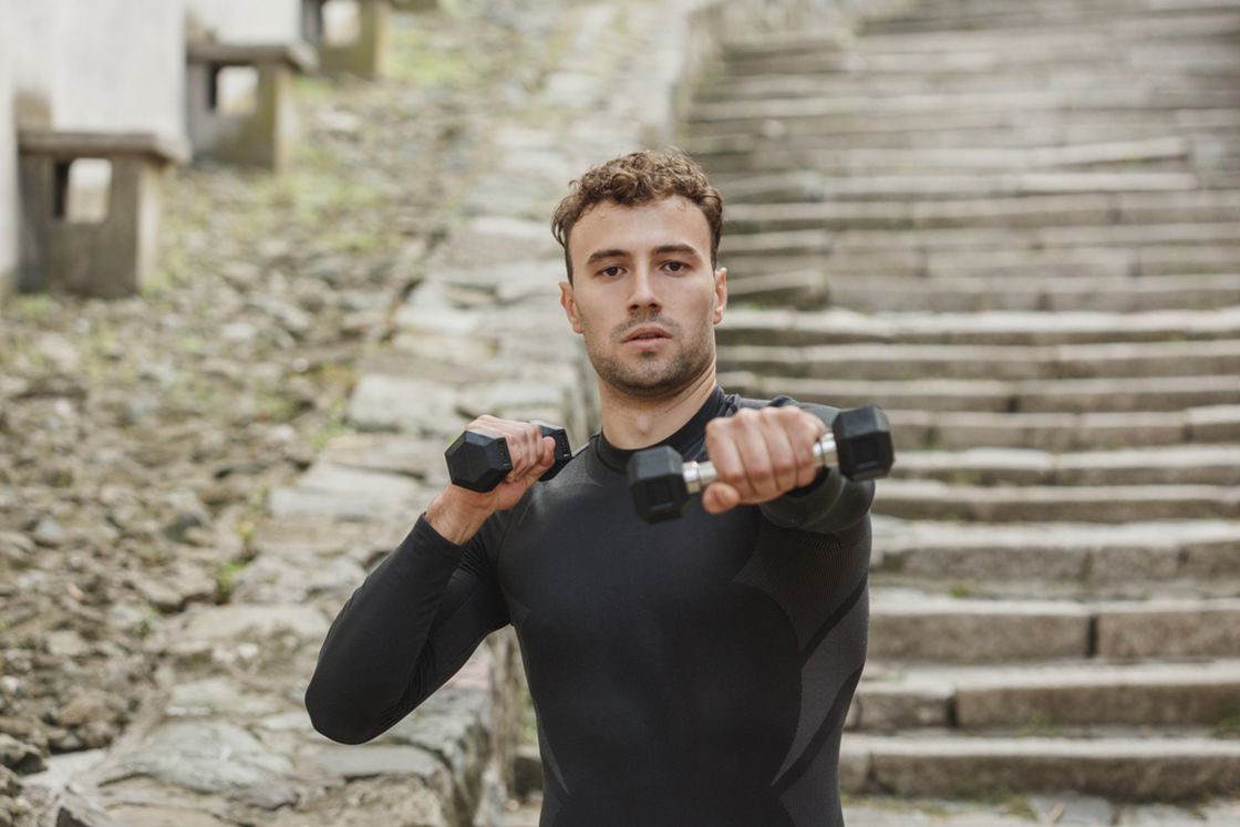Man using dumbbells while exercising outdoors