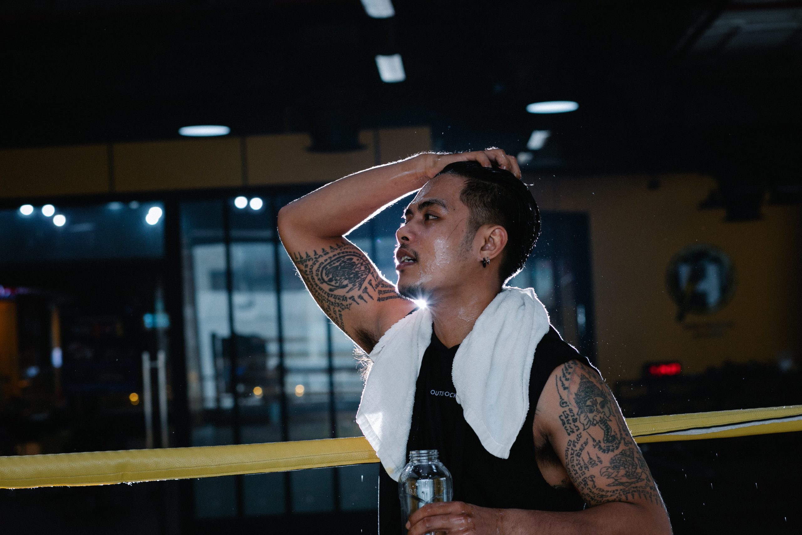 A man sweating after a workout while holding a water bottle