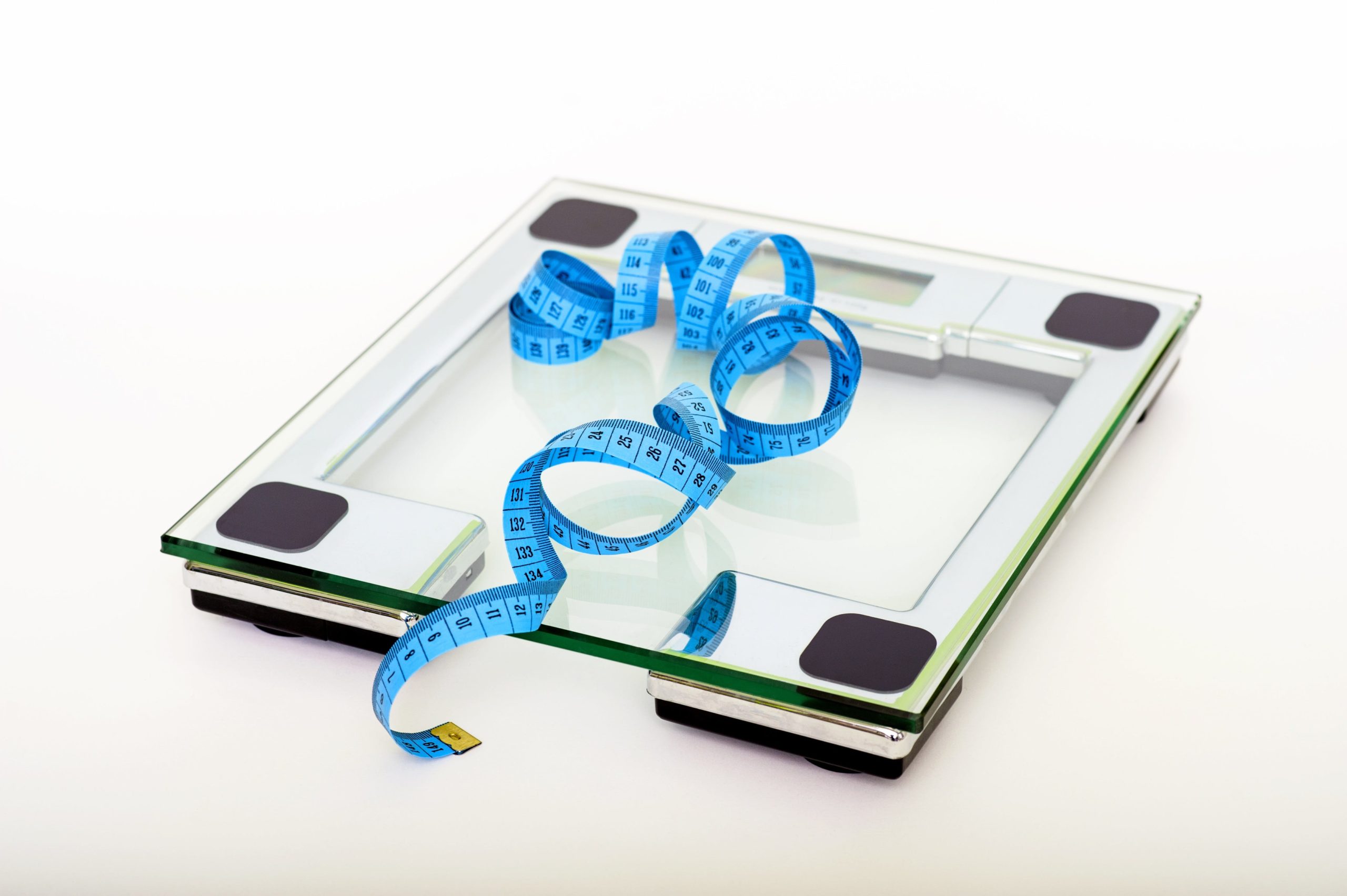A weighing scale with blue tape measure on top of it