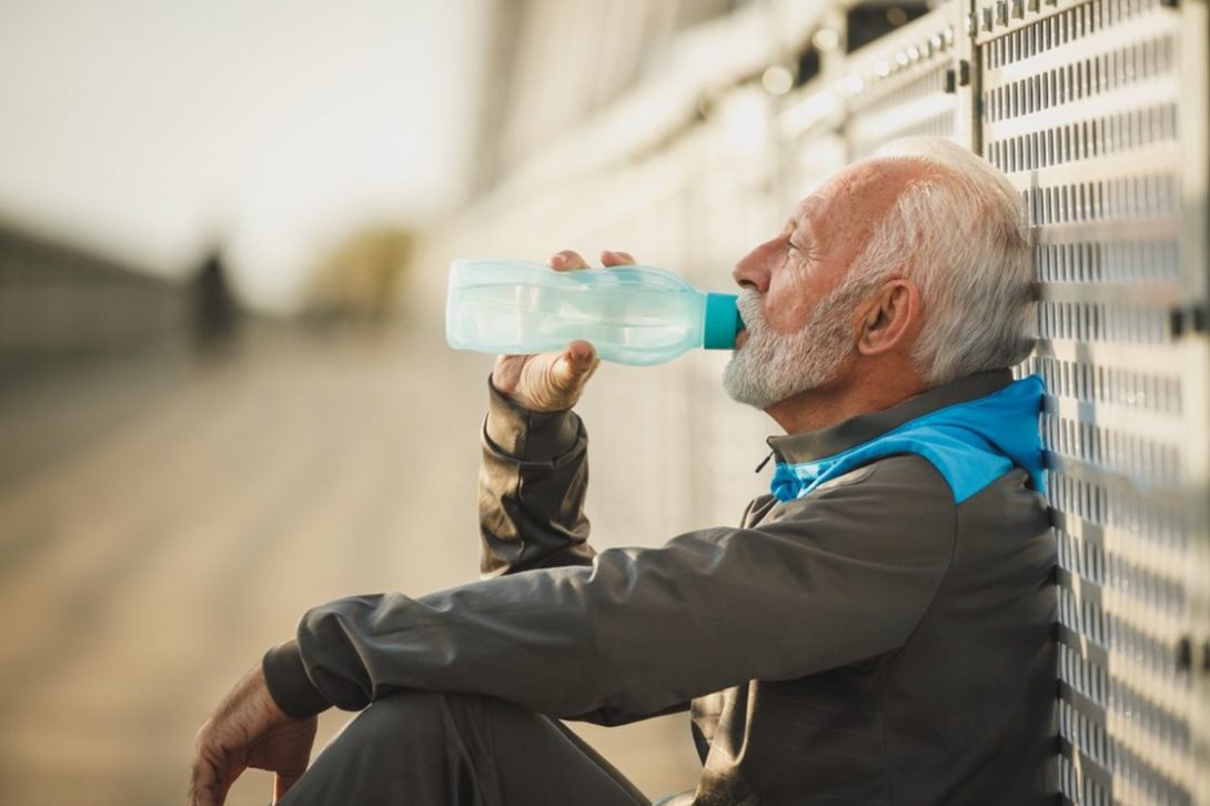 Man sitting down while drinking from a water tumbler