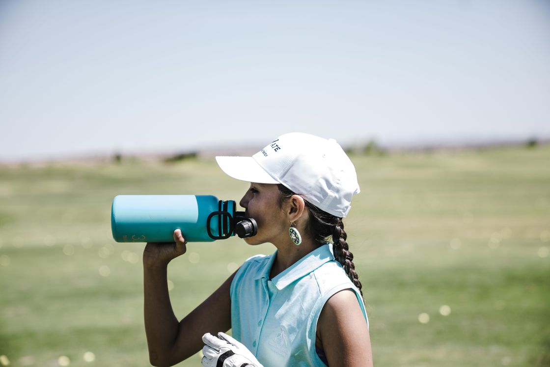 Woman drinking from an aqua green water bottle