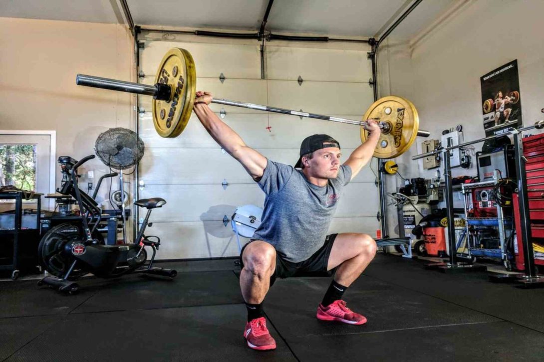 Man squatting down to lift a barbell over his head