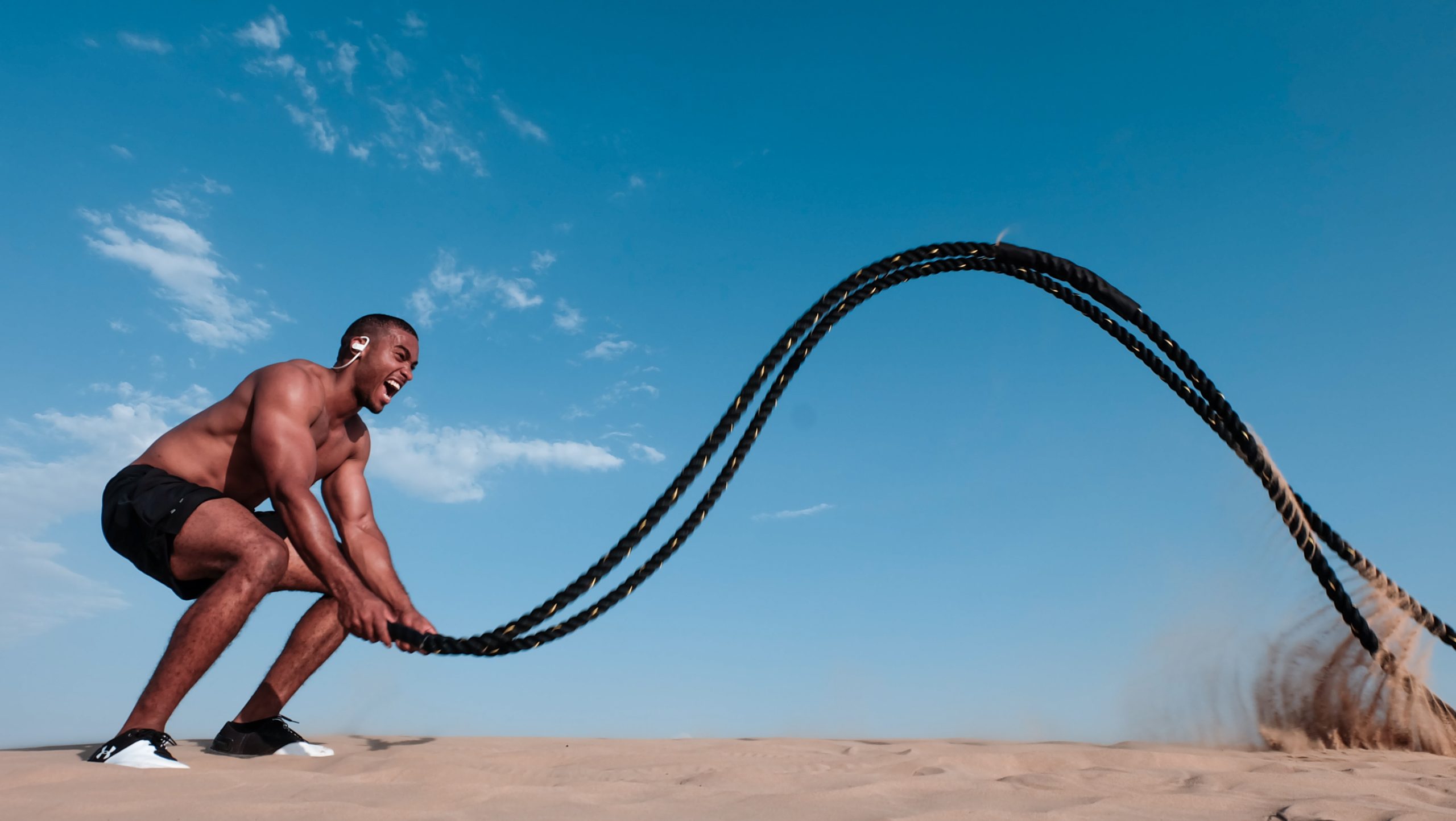 A man doing an intense rope training on a sandy ground