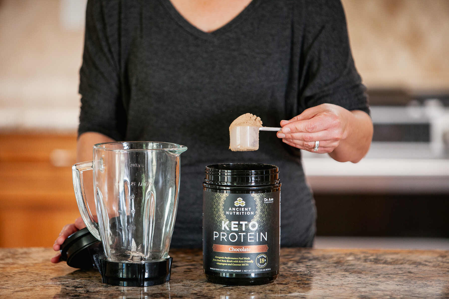 Woman scooping out protein powder into a blender