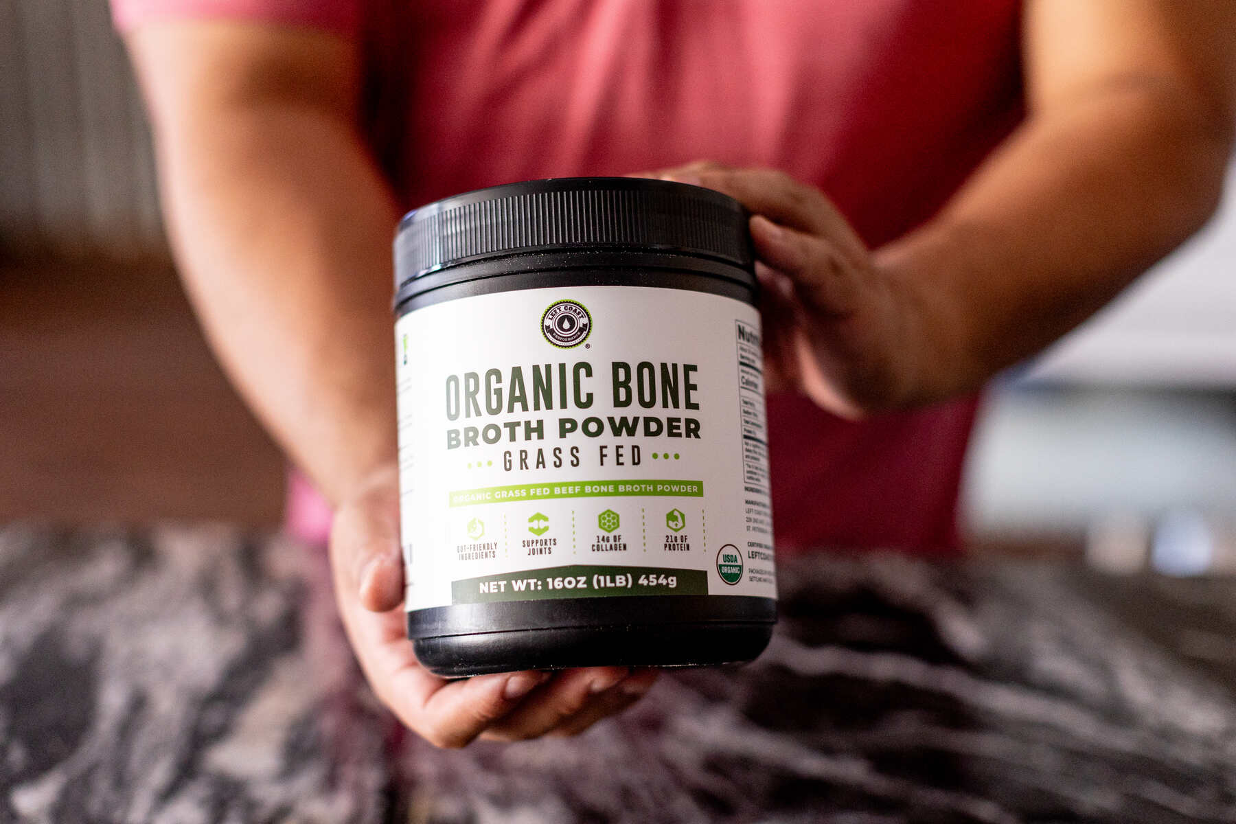 Man holding a bottle of Organic Bone Broth Powder