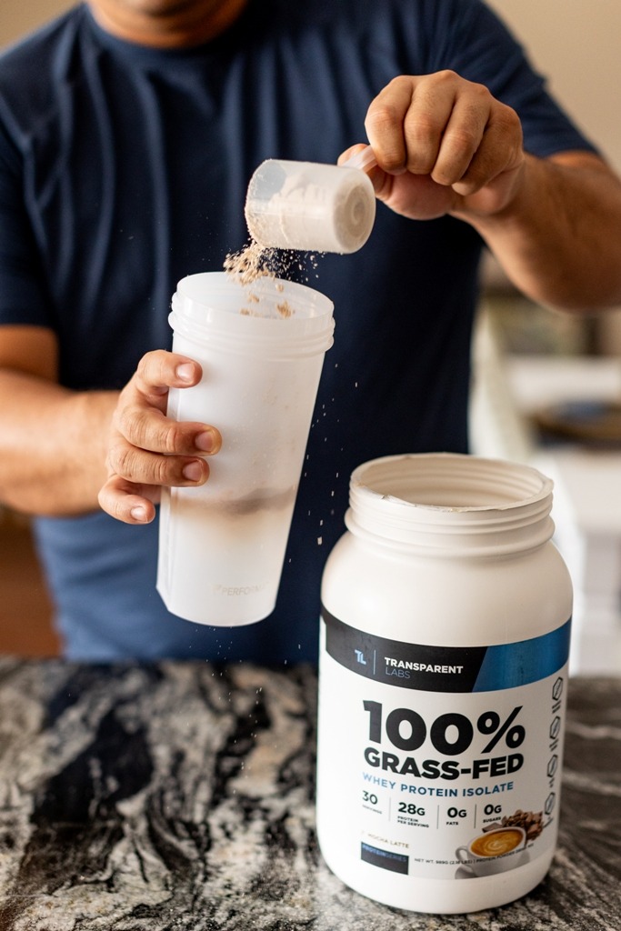 Man pouring a scoop of protein powder into a water bottle