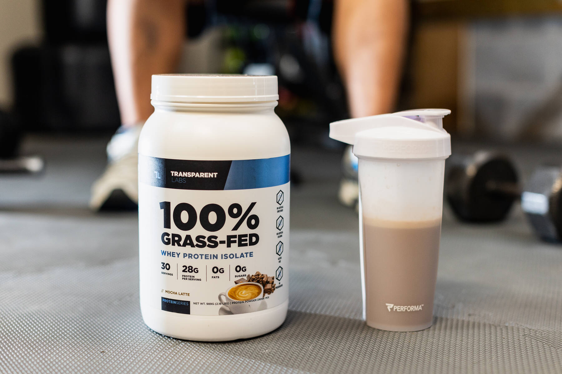Transparent Labs whey protein isolate container next to a protein shake on a gray gym floor
