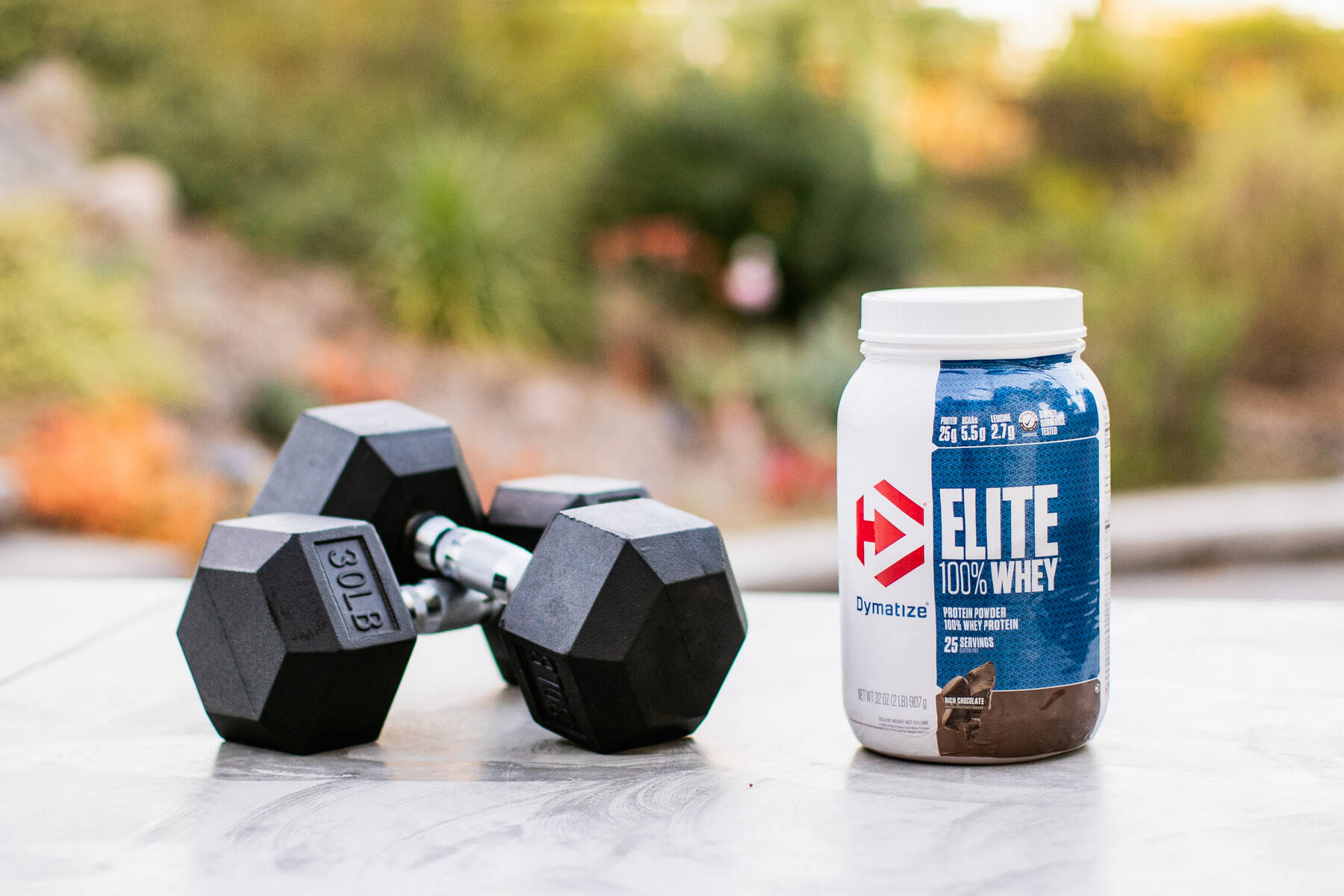 Dumbbells and whey protein container on an outdoor table