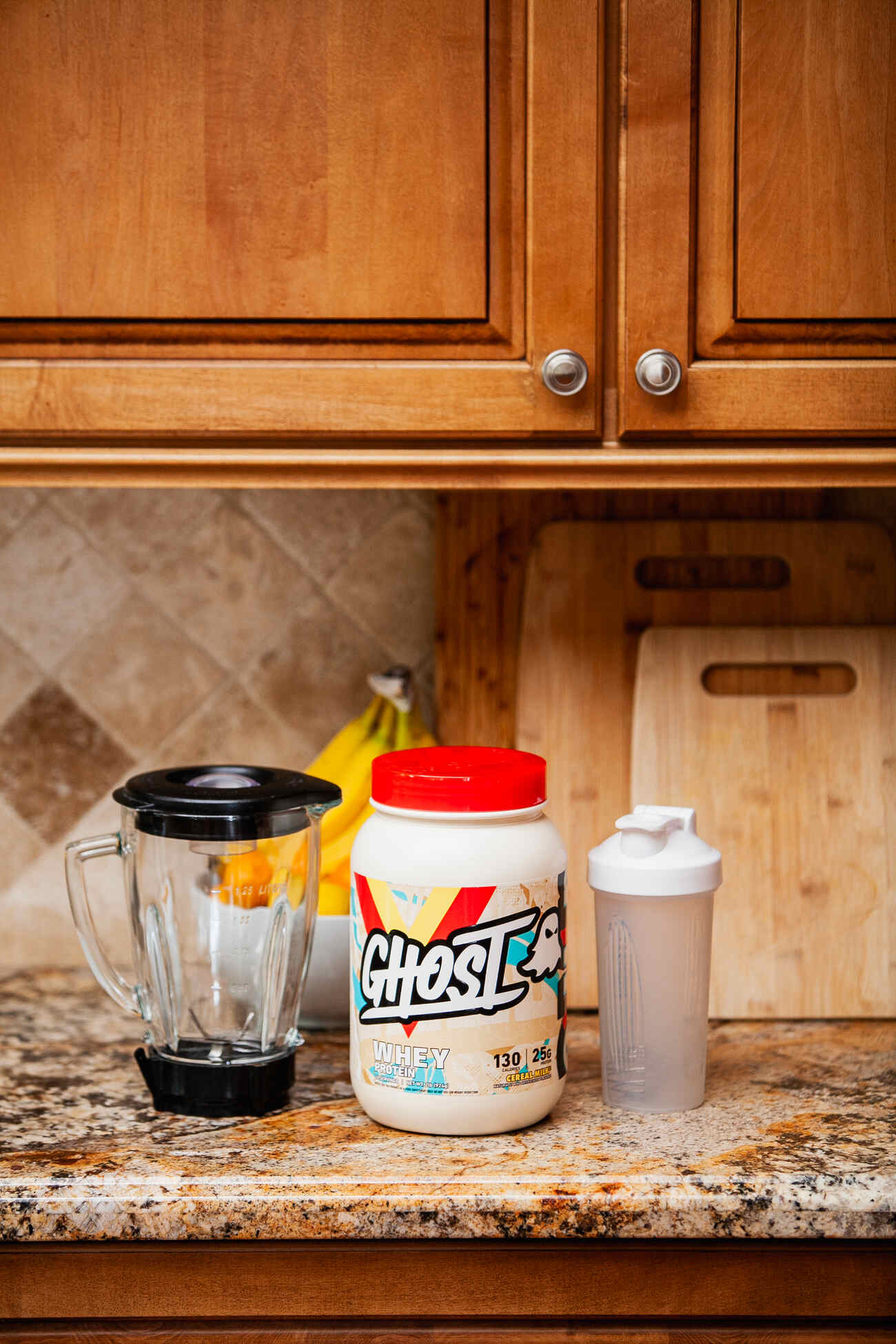 A protein powder jar, shaker bottle, and blender on a kitchen countertop