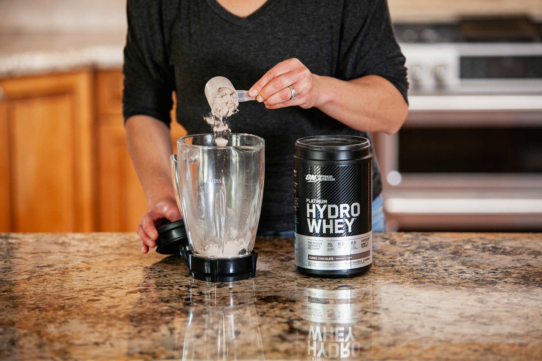 Woman adding protein powder to a blender