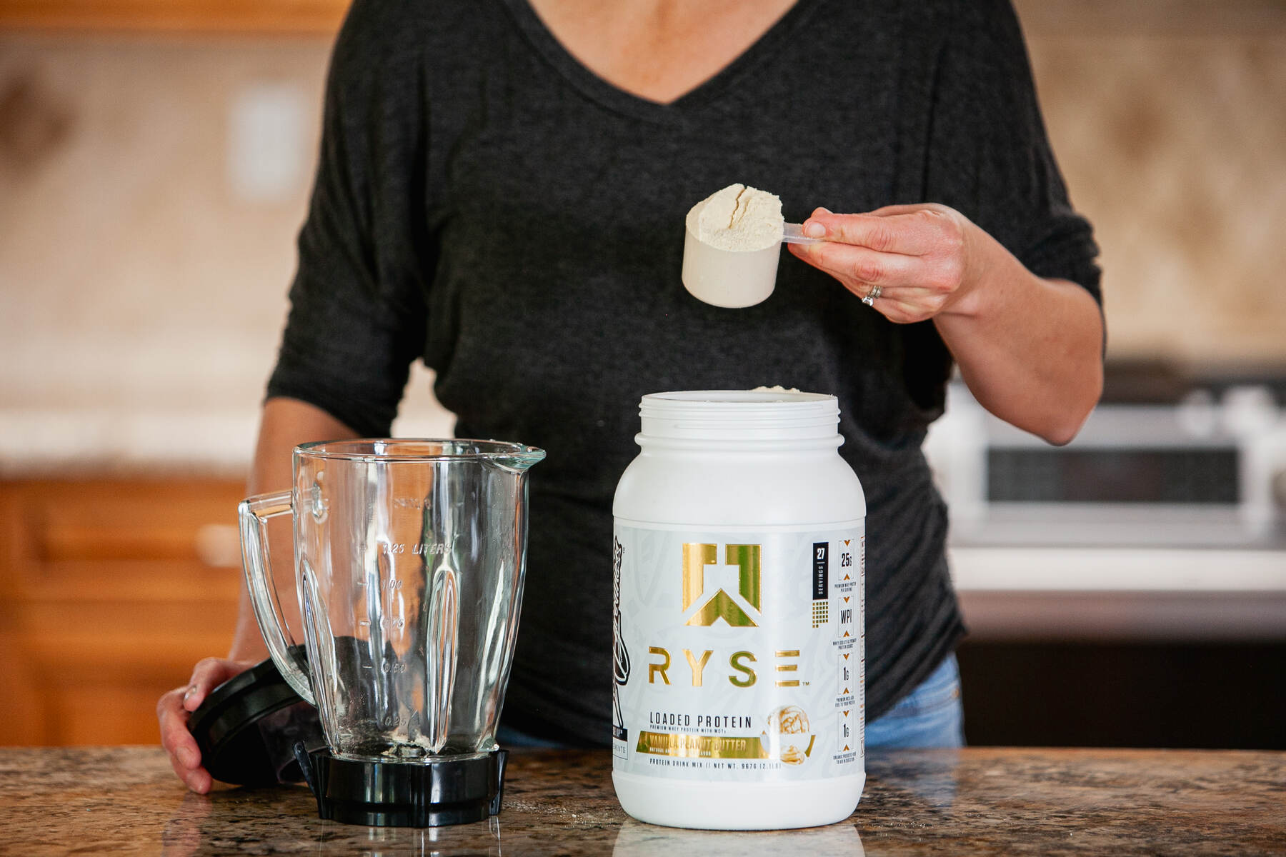 A woman measuring protein powder in kitchen