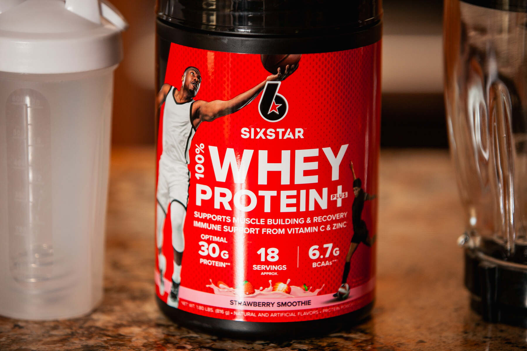 A "Six Star Whey Protein" container with an athlete's image, next to a shaker bottle, emphasizing muscle support and immune health