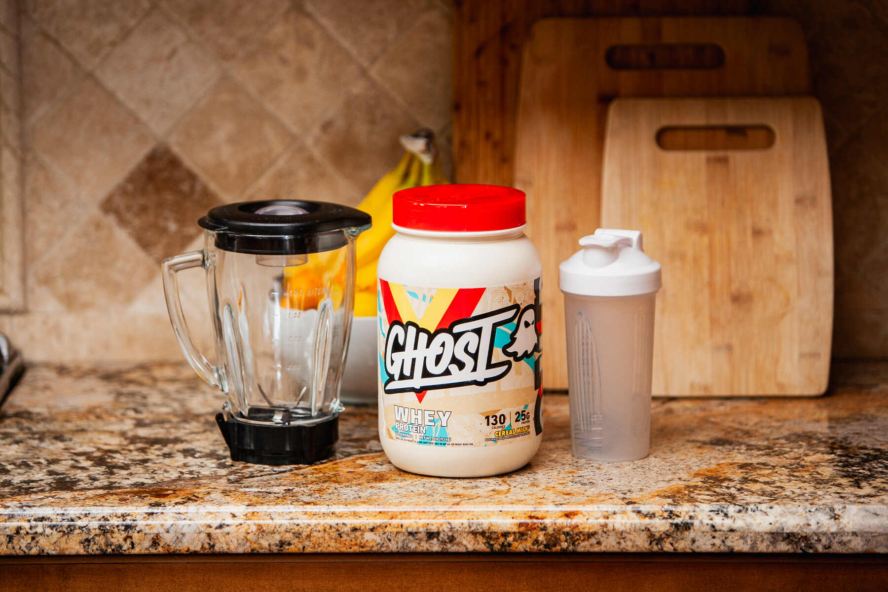 Whey protein, blender, and shaker on kitchen countertop