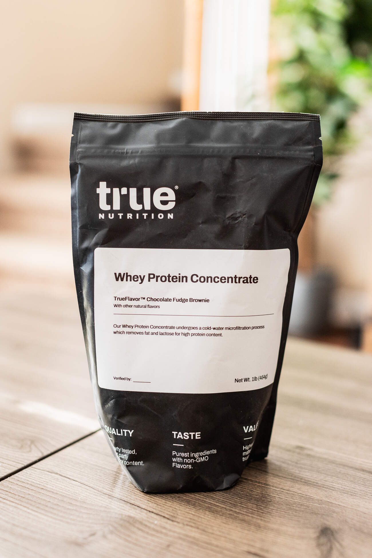A bag of whey protein concentrate on a wooden table with soft background lighting
