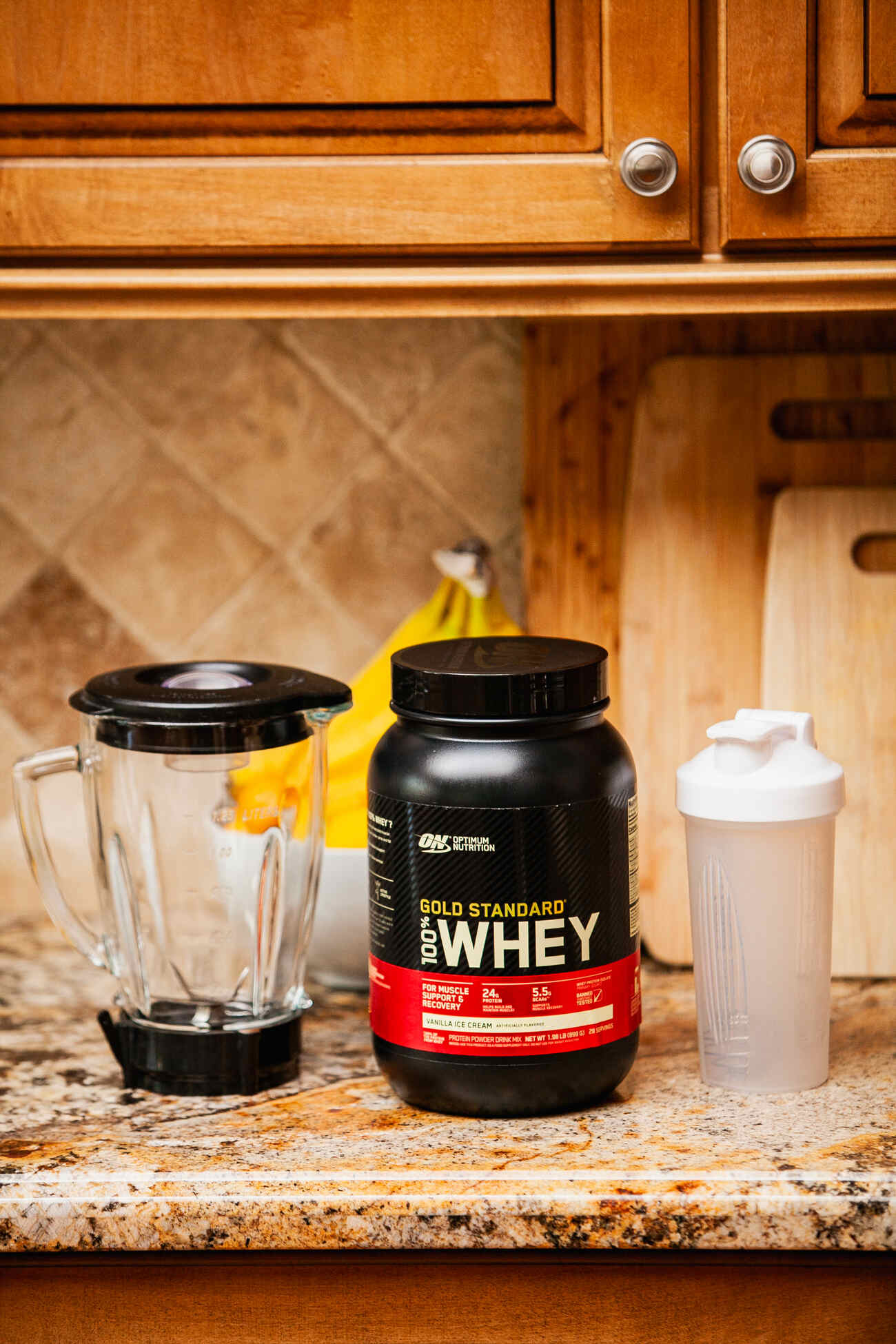 Protein powder, blender, and shaker on kitchen countertop