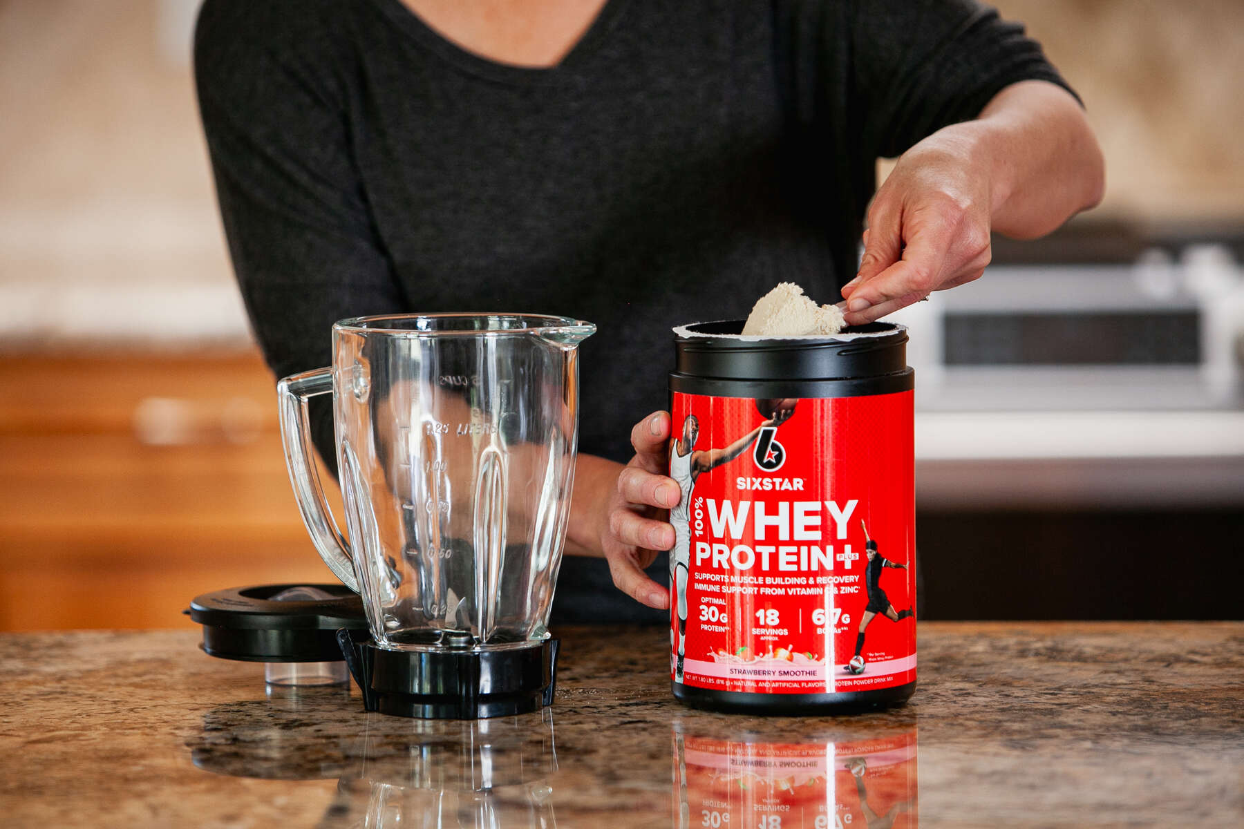 A woman scooping strawberry flavored whey protein